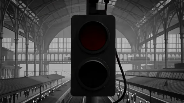 A red railway signal framed against the steel roof of a monochrome station.